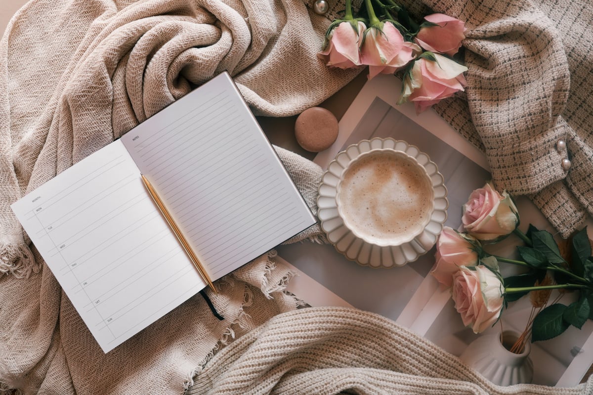 Peaceful desk setup with journal, coffee, and flowers